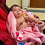 Lily is registered to the contest to win money with this photo: baby, blanket, pacifier, hand, indoor, red_jacket, pink, child, infant, cozy, floor, toy_pattern, foot, curious, wrapped, soft_texture, person, holding, seated, expression
