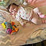 baby, infant, blanket, plush_toy, clothing, striped_pants, floral_sweater, pink, soft_texture, elephant_design, lying_down, indoor, child, cute, toy, pastel_colors, smiling, face, small_hands, comfort