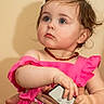 toddler, child, baby, pink_dress, blue_eyes, remote_control, hands, adult_hands, portrait, indoor, curious, looking_away, jewelry, necklace, short_hair, skin, human, person, cute, innocent