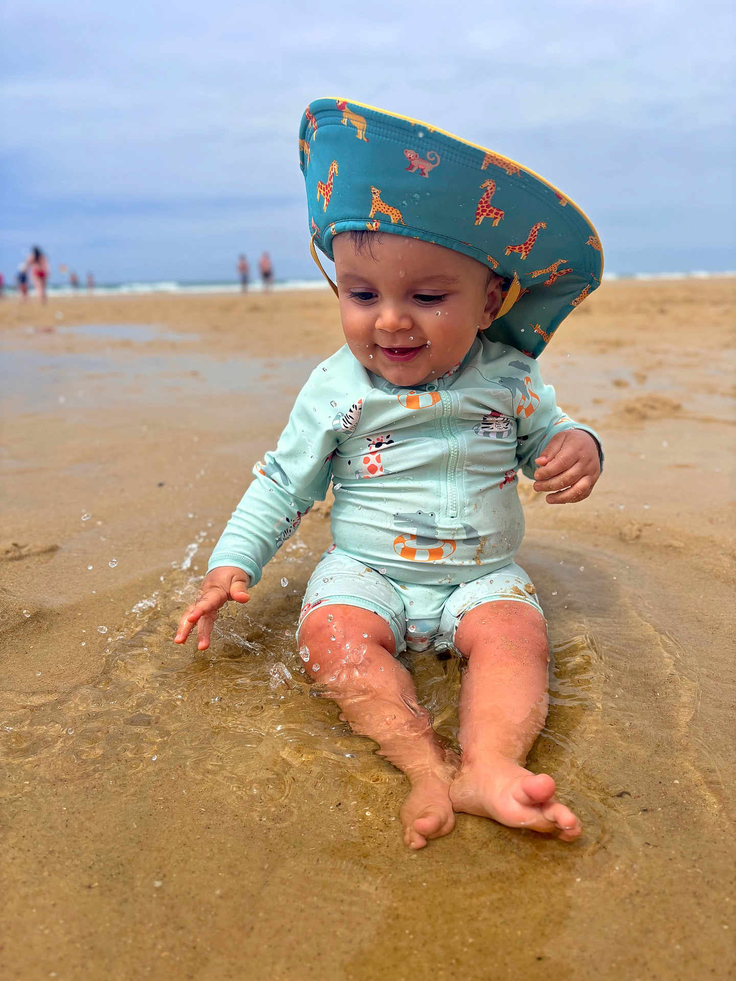 Gabriel participe au concours pour gagner de l'argent avec cette photo : toddler, child, beach, sand, water, splashing, sun_hat, swimwear, animal_print, happy, playing, summer, outdoor, sea, waves, fun, water_droplets, nature, vacation, sun_protection
