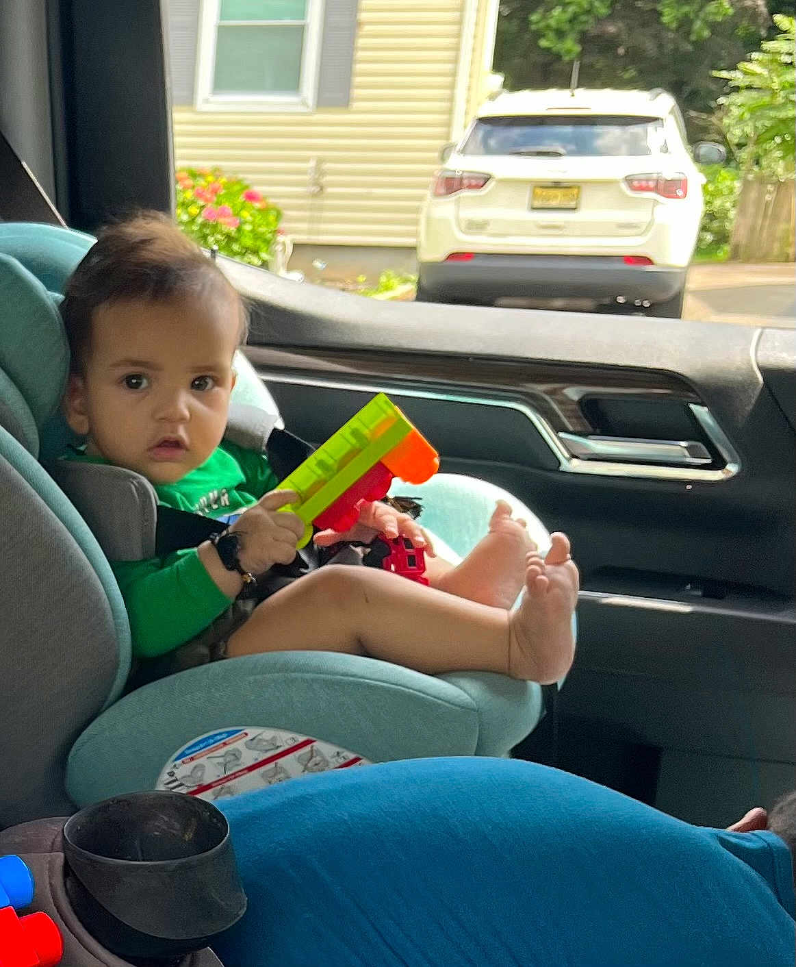 Ayasha joined the competition — help win amazing prizes! child, toddler, car_seat, toy, barefoot, car_interior, window, seatbelt, person, green_clothing, foot, hand, vehicle, parking, outside, daylight, face, hair, seat, plastic_toy
