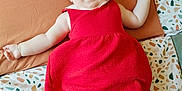 Eloane participe au concours pour gagner de l'argent avec cette photo : baby, infant, red_dress, smiling, lying_down, blanket, cushion, happy, child, cute, indoors, pale_skin, patterned_fabric, small_hands, small_feet, cheerful, portrait, head, person, soft_light