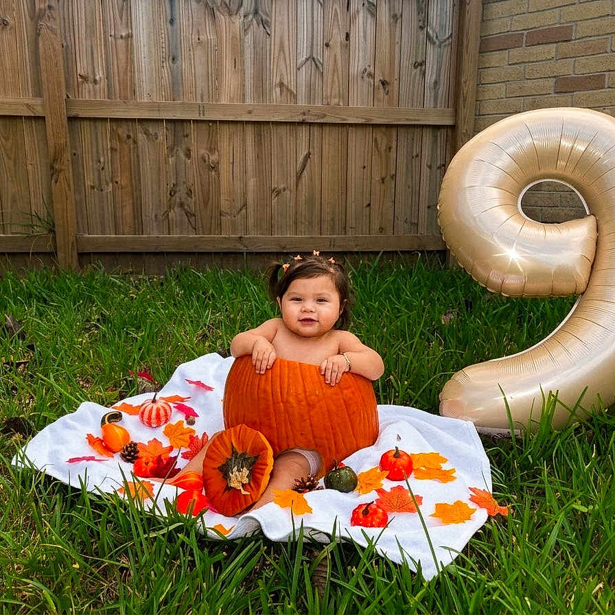 Hailey is registered to the contest to win money with this photo: baby, child, pumpkin, autumn, fall, outdoor, grass, garden, balloon, number_nine, birthday, harvest, leaves, orange, blanket, portrait, smiling, sitting, costume, seasonal