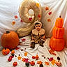 child, toddler, baby, portrait, sitting, autumn, fall, pumpkins, pumpkin, leaves, autumn_leaves, balloon, gold_balloon, floral_dress, headband, brown_boots, seasonal_decor, pinecones, studio_setup, orange