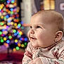 baby, child, face, earring, smile, happy, indoor, portrait, christmas_lights, blurred_background, holiday, cute, soft_light, infant, clothing, long_sleeve, pink, floral_pattern, hand, closeup