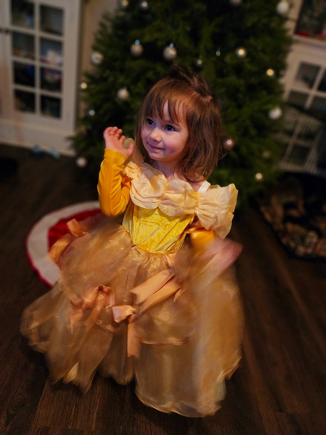 Katalina is registered to the contest to win money with this photo: baby_toddler_clothing, child, christmas_decoration, christmas_ornament, christmas_tree, conifer, dress, event, flooring, fun, happy, holiday, joy, ornament, peach, person, plant, ruffle, sitting, smile