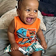 Malachi joined the competition — help win amazing prizes! toddler, child, smiling, dinosaur_print, orange_tank_top, shorts, bed, pigtails, happy, indoors, cute, person, clothing, sitting, feet, portrait, baby, furniture, cushion, skin