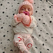 Amelia is registered to the contest to win money with this photo: baby, infant, pink_hat, knitwear, mittens, pacifier, blanket, stars, moon, sleeping, cute, child, soft_texture, striped_pants, cozy, lying_down, indoors, small_person, warm_clothing, adorable