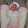baby, infant, pacifier, headband, pink_clothing, baby_bed, blanket, cozy, cute, child, newborn, soft_toys, resting, indoors, sleepwear, baby_girl, comfort, baby_accessories, lying_down, portrait