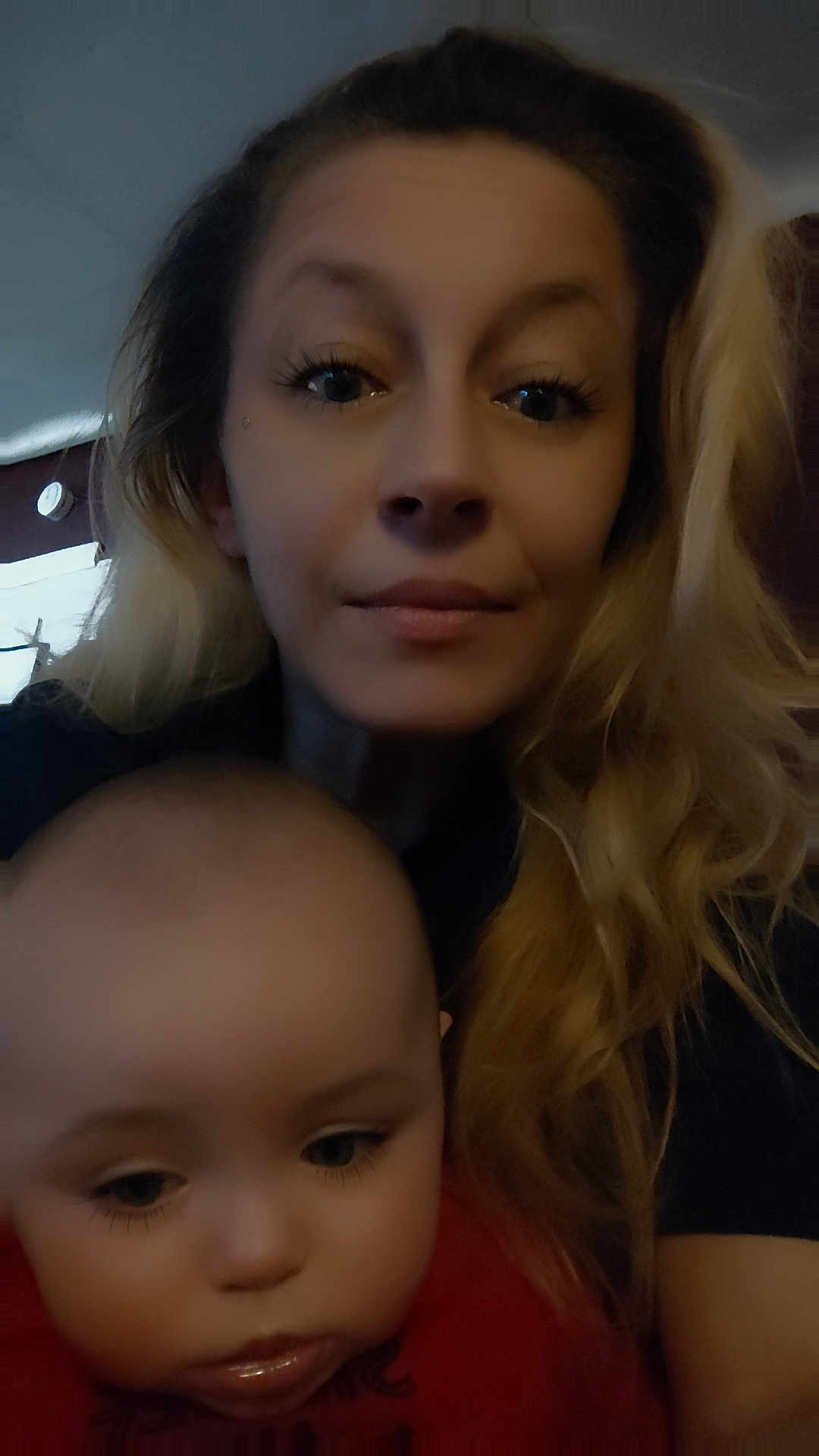 Amelia is registered to the contest to win money with this photo: woman, baby, selfie, portrait, indoor, blond_hair, long_hair, child, face, eyes, baby_face, mother_and_child, closeup, low_light, casual, cuddling, skin, expression, home_interior, blur