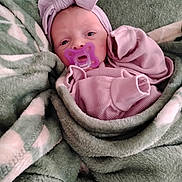 Amelia is registered to the contest to win money with this photo: baby, pacifier, blanket, headband, pink_clothing, wrapped, newborn, face, infant, cute, sleepwear, soft_texture, cozy, portrait, child, indoors, resting, young, human, comfort