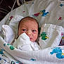 newborn, baby, blanket, hospital, crib, duck_pattern, swaddled, infant, medical_tubes, bed, white_clothing, face, eyes, skin, cute, child, lying_down, indoors, cozy, small