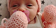 Amelia joined the competition — help win amazing prizes! baby, infant, pacifier, knit_hat, mittens, pink, sleepy, blanket, stars, moons, closeup, face, cute, newborn, soft_texture, warm_clothing, lying_down, cozy, child, portrait