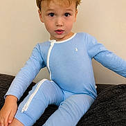 саймон is registered to the contest to win money with this photo: child, toddler, blue_onesie, blonde_hair, curious_expression, sitting, indoor, couch, cozy, portrait, young_child, casual_clothing, zipper, comfortable, looking_at_camera, cute, innocent, light_background, home, relaxed