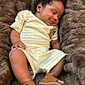 baby, sleeping, infant, yellow_striped_clothing, winnie_the_pooh_patch, brown_sandals, curly_hair, soft_blanket, cozy, smiling, cute, portrait, child, resting, indoor, furniture, closeup, peaceful, toddler, skin