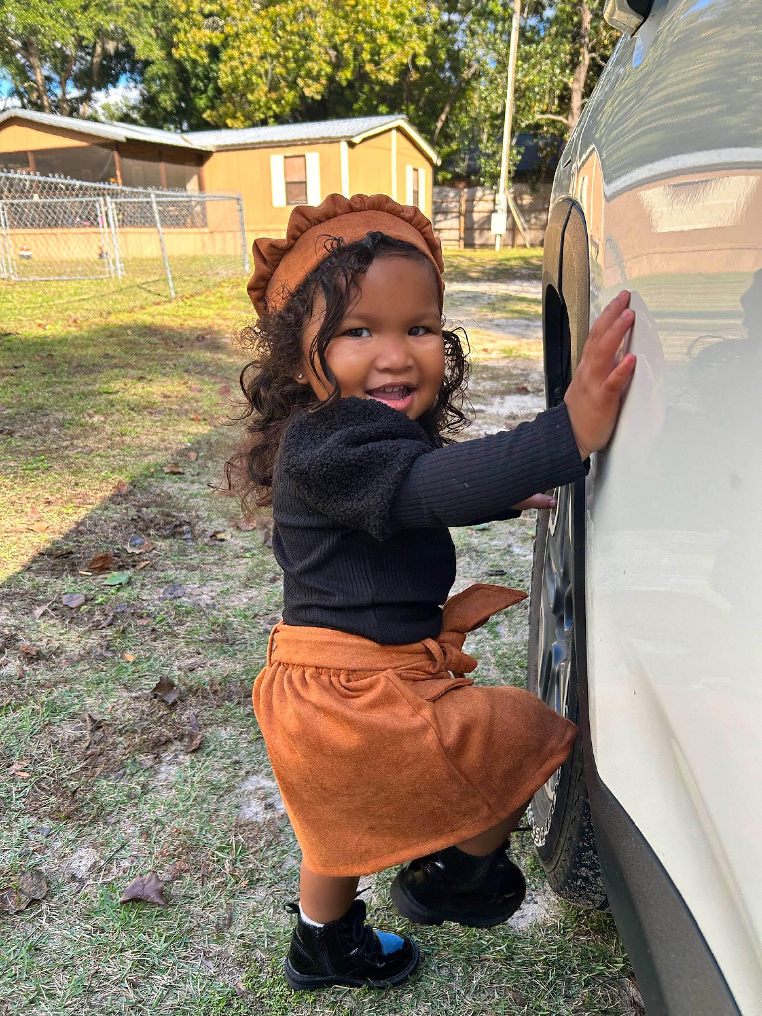 Layla is registered to the contest to win money with this photo: automotive_design, automotive_exterior, automotive_lighting, automotive_tire, bumper, car, fender, grass, happy, hood, motor_vehicle, person, plant, smile, tints_and_shades, tire, toddler, tree, vehicle, vehicle_door