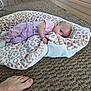 Delilah is registered to the contest to win money with this photo: baby, blanket, leopard_print, flooring, rug, wooden_floor, infant, person, hand, foot, cozy, indoor, pink_clothing, texture, pattern, lying_down, curious, soft, casual, home
