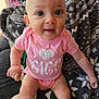 Delilah is registered to the contest to win money with this photo: baby, infant, pink_onesie, sitting, blanket, patterned_blanket, cute, face, big_eyes, child, indoors, clothing, smiling, person, skin, head, arm, leg, happy, young_child