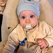 Jules participe au concours pour gagner de l'argent avec cette photo : baby, pacifier, hat, blue_eyes, blanket, cushion, clothing, cute, face, hand, infant, indoors, person, plush, portrait, sitting, soft_toys, toddler, wearing_hat, young_child