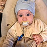 baby, pacifier, hat, blue_eyes, blanket, cushion, clothing, cute, face, hand, infant, indoors, person, plush, portrait, sitting, soft_toys, toddler, wearing_hat, young_child