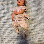 Isabella is registered to the contest to win money with this photo: baby, infant, child, pink_clothing, headband, carpet, floor, lying_down, looking_up, sock, cute, indoors, texture, footwear, person, small_child, soft_lighting, casual, cozy, portrait