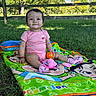 Isabella is registered to the contest to win money with this photo: baby, child, infant, sitting, smiling, portrait, outdoor, grass, park, blanket, colorful_blanket, orange_ball, toy, pink_clothing, socks, wooden_fence, trees, sunlight, playtime, happy
