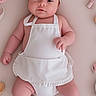 baby, infant, chef_hat, apron, cute, lying_down, kitchen_toys, soft_skin, pastel_colors, child, adorable, chubby_arms, chubby_legs, indoors, portrait, headwear, playful, smiling, baby_clothes, cooking_theme