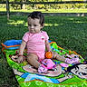 baby, blanket, cartoon_blanket, child, fence, grass, nature, orange_ball, outdoor, park, pink_clothing, playtime, polka_dots, portrait, sitting, smiling, socks, sunlight, toy, trees