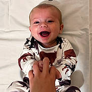 Walker joined the competition — help win amazing prizes! baby, infant, smiling, happy, hand, holding, clothing, animal_print, lying_down, white_background, person, child, cute, joyful, face, skin, eyes, mouth, expression, indoor