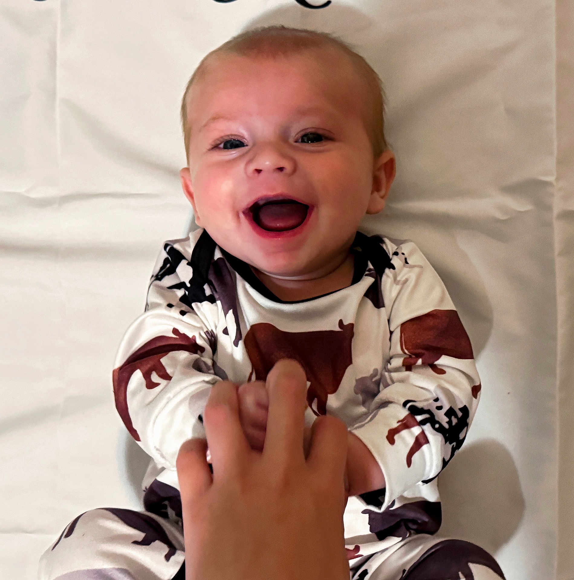 Walker joined the competition — help win amazing prizes! baby, infant, smiling, happy, hand, holding, clothing, animal_print, lying_down, white_background, person, child, cute, joyful, face, skin, eyes, mouth, expression, indoor