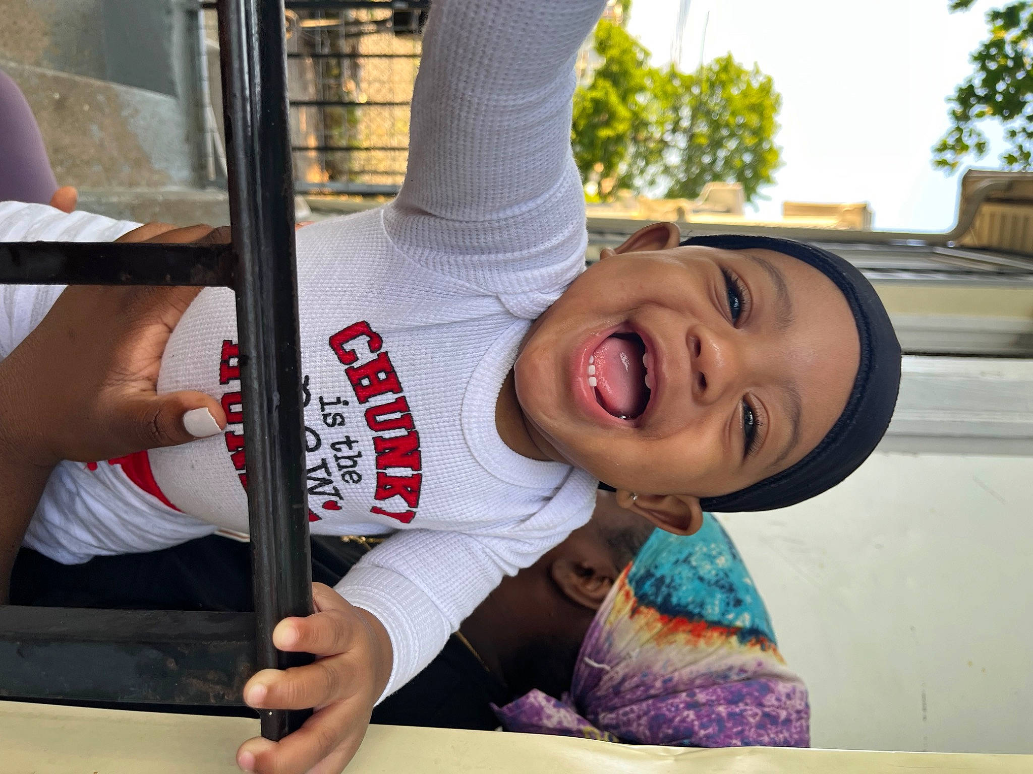 Kayden is registered to the contest to win money with this photo: child, elbow, facial_expression, fun, gesture, hand, happy, laugh, leisure, person, plant, recreation, sky, smile, sportswear, t_shirt, toddler, tree, vacation, window