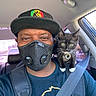 Luna is registered to the contest to win money with this photo: man, mask, black_cap, car, seatbelt, kitten, black_and_white_cat, cat_tag, shoulder, pet, indoor, window, daylight, backseat, face, portrait, animal, human, sitting, looking