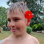 Yaël participe au concours pour gagner de l'argent avec cette photo : background, boy, child, face, flower, garden, greenery, happy, head, nature, orange_flower, outdoor, plant, portrait, shirtless, smile, summer, trees, wet_hair, young