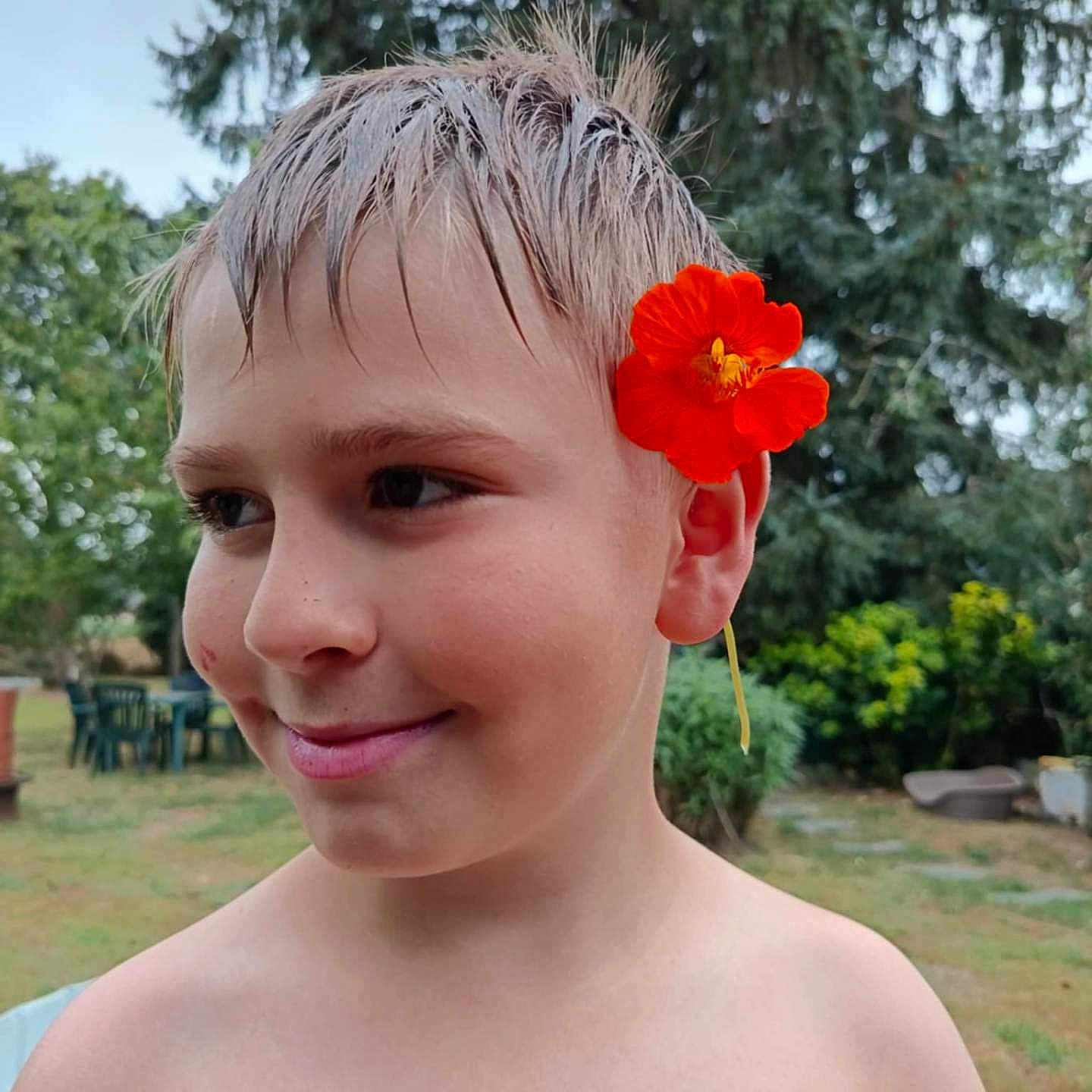 Yaël participe au concours pour gagner de l'argent avec cette photo : background, boy, child, face, flower, garden, greenery, happy, head, nature, orange_flower, outdoor, plant, portrait, shirtless, smile, summer, trees, wet_hair, young