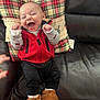 Anthony joined the competition — help win amazing prizes! baby, black_pants, brown_slippers, child, clothing, cozy, cute, furniture, happy, indoor, infant, joyful, laughing, leather_couch, person, plaid_pillow, portrait, red_vest, sitting, smiling