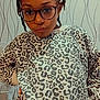 child, glasses, braids, leopard_print, sweatshirt, matching_outfit, indoor, fan, wallpaper, pattern, standing, confident, portrait, casual_clothing, person, fashion, young, cute, stylish, home