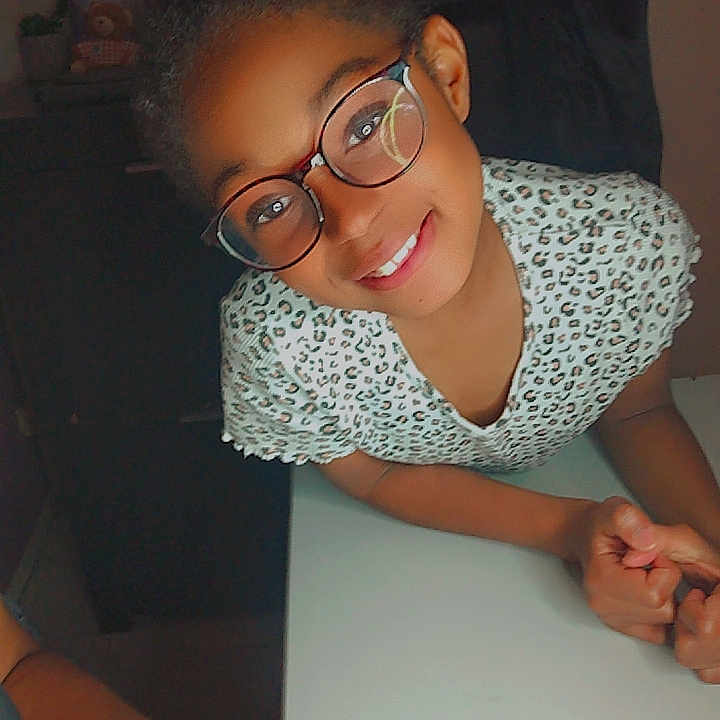 Jalina participe au concours pour gagner de l'argent avec cette photo : arm, casual, child, clothing, eyewear, face, friendly, furniture, glasses, hand, happy, human, indoor, leisure, person, portrait, skin, smile, table, young