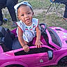 baby, child, toddler, smiling, portrait, toy_car, pink_car, outdoor, garden, grass, bow, dress, cherries, steering_wheel, playtime, vehicle, sitting, standing, adults, happy