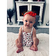 Marnie joined the competition — help win amazing prizes! baby, child, headband, red_bow, blue_eyes, cherry_pattern, dress, sitting, white_rug, fireplace, cozy, indoor, carpet, curious, portrait, cute, homedecor, floor, infant, hands
