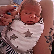 Teddy joined the competition — help win amazing prizes! newborn, baby, sleeping, wrapped, blanket, stars, tattoo, arm, hand, nails, blue_nail_polish, striped_clothing, closeup, indoor, person, infant, skin, face, peaceful, resting