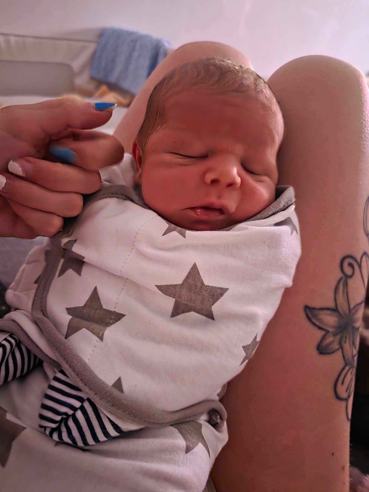 Teddy joined the competition — help win amazing prizes! newborn, baby, sleeping, wrapped, blanket, stars, tattoo, arm, hand, nails, blue_nail_polish, striped_clothing, closeup, indoor, person, infant, skin, face, peaceful, resting