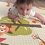 baby, child, play_mat, floor, indoor, cute, curious, person, face, hair, eyes, toddler, white_clothing, pattern, animal_illustration, tree_illustration, colorful, soft_texture, expression, infant
