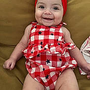 Mia joined the competition — help win amazing prizes! baby, checkered_pattern, cheerful, child, chubby_legs, clothing, couch, cute, furniture, happy, headwear, indoors, infant, portrait, red_dress, red_headband, seated, skin, smiling, stars