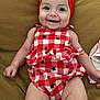 baby, checkered_pattern, cheerful, child, chubby_legs, clothing, couch, cute, furniture, happy, headwear, indoors, infant, portrait, red_dress, red_headband, seated, skin, smiling, stars