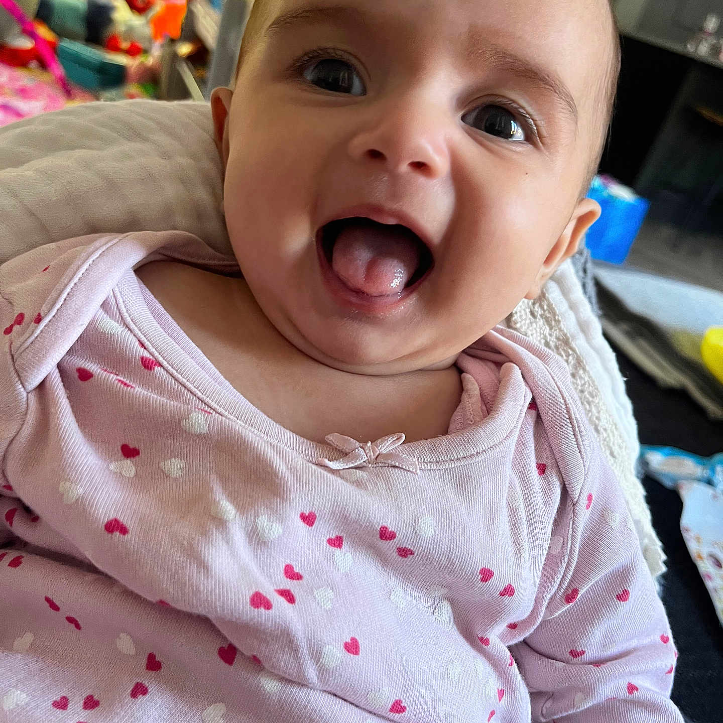 Ava joined the competition — help win amazing prizes! baby, blanket, casual, child, closeup, cute, happy, heart_pattern, home, indoor, infant, person, pink_clothing, playful, portrait, smiling, soft_lighting, tongue_out, toy, young_child