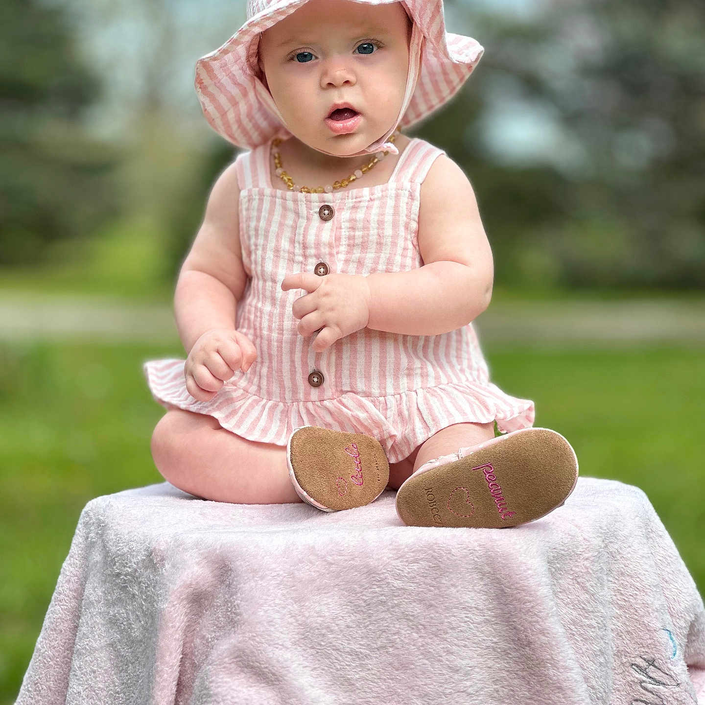 Ivory joined the competition — help win amazing prizes! baby, baby_girl, blanket, child, closeup, curious_expression, cute, greenery, infant, natural_light, outdoor, pink_hat, portrait, sitting, small_shoes, soft_texture, striped_clothing, summer, sunhat, young_child