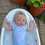 Margot is registered to the contest to win money with this photo: baby, bathtub, water, toy, rubber_toy, flower_pot, flowers, outdoor, pavement, infant, child, blue_onesie, cute, relaxing, summer, playtime, garden, plant, green, yellow