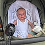 Margot is registered to the contest to win money with this photo: baby, onesie, stroller, toy, duck, fan, infant, child, white_clothing, green_stroller, blanket, fabric, seat, outdoor, person, cute, face, head, small_toy, comfort