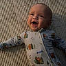 baby, smiling, infant, onesie, clothing, carpet, floor, happy, face, child, cute, pattern, animal_print, home, indoors, person, portrait, baby_girl, baby_boy, playful