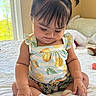 baby, child, infant, sitting, bed, window, natural_light, pigtails, playful_hair, cute, smiling, socks, clothing, patterned_outfit, indoor, soft_light, skin, hand, fingers, expression